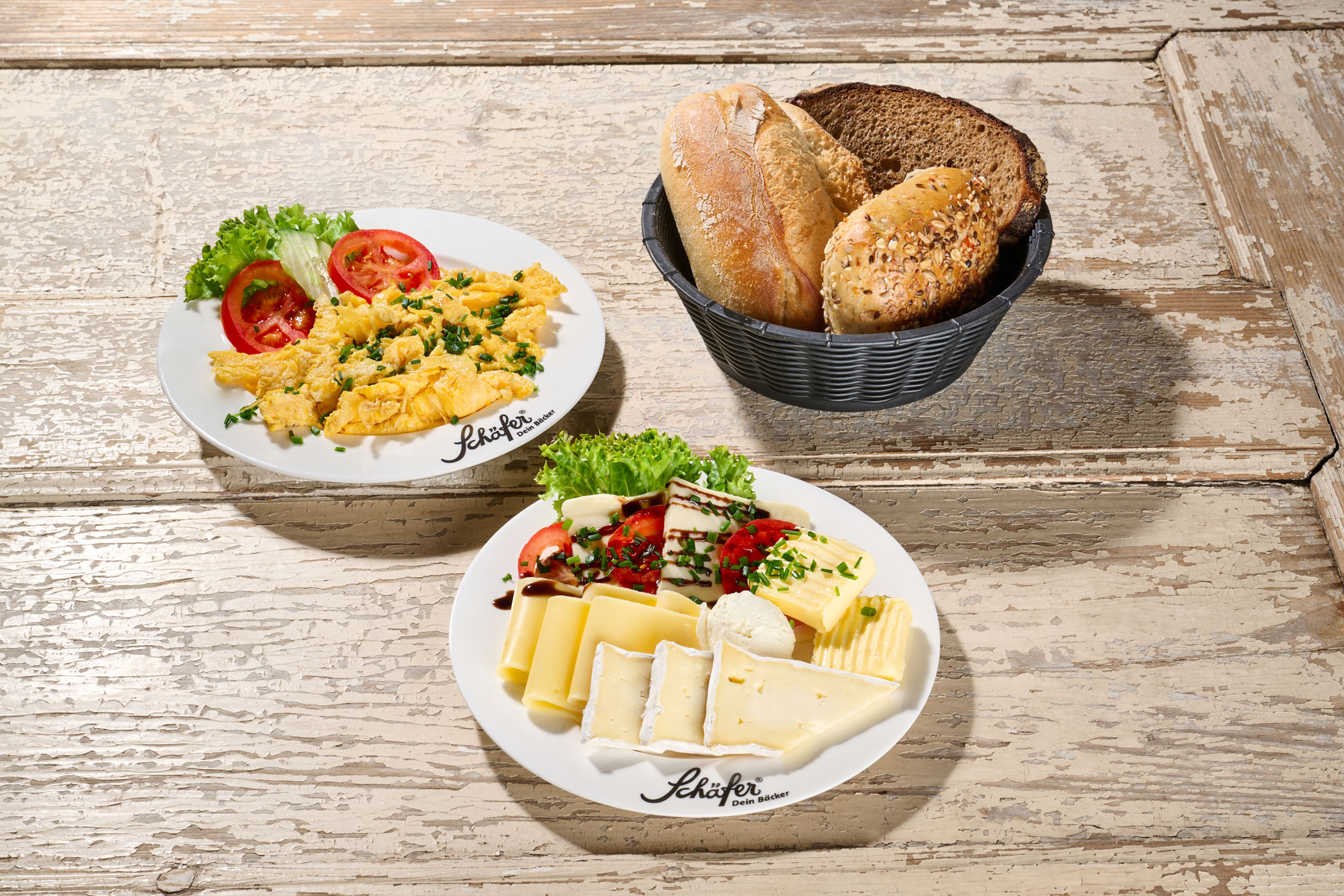 Schäferstündchen-veggie Rustikaler Teller mit Rührei, Butter, Salat und einem Körnerbrötchen auf hellem Holz