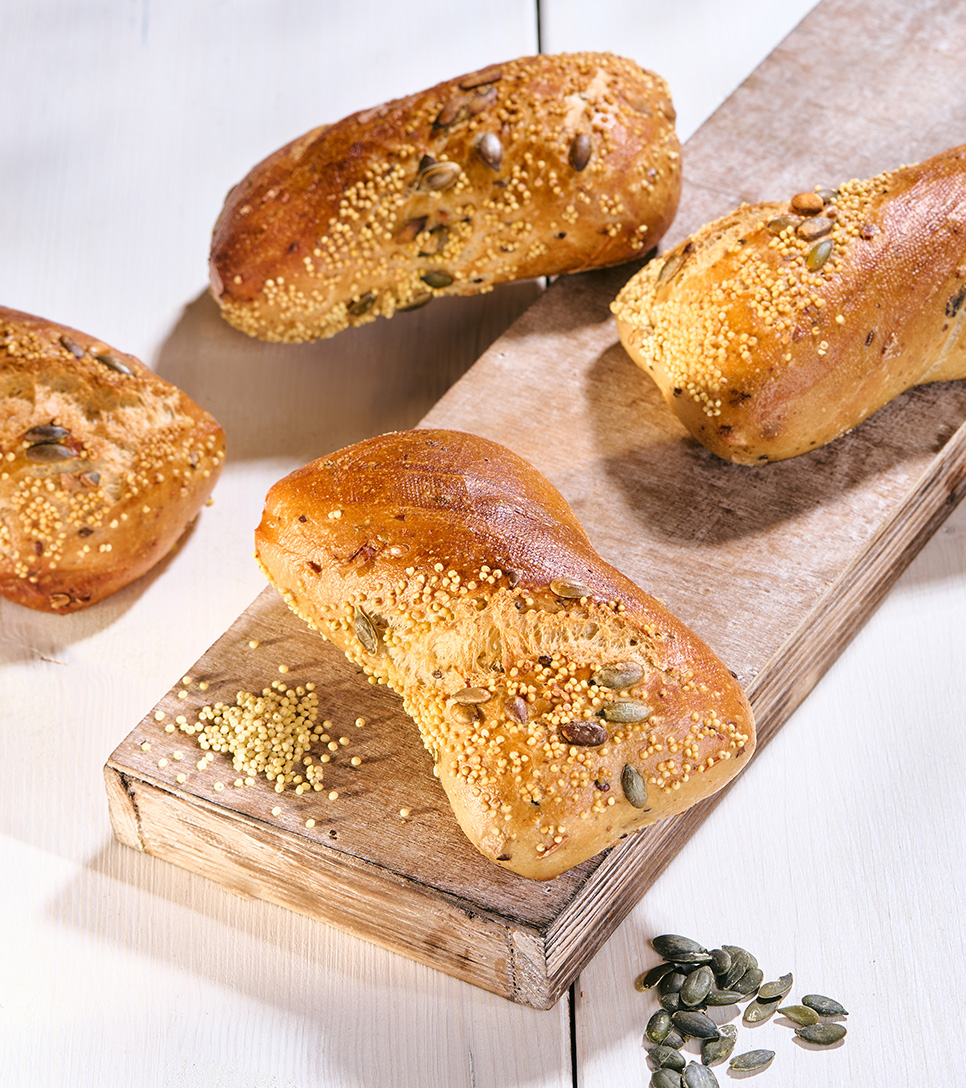 Kürbiskernbrötchen belegt mit Käse, Tomate, Salat und Zwiebel auf Backpapier