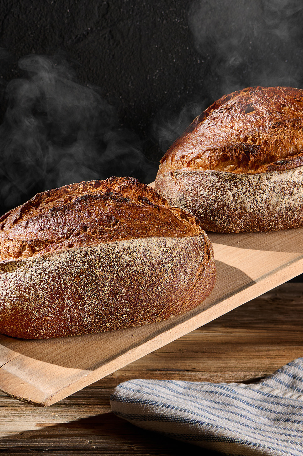 Dinkelvollkornbrot mit Sonnenblumenkernen und Frischkäse auf Holzbrett, daneben Körner.